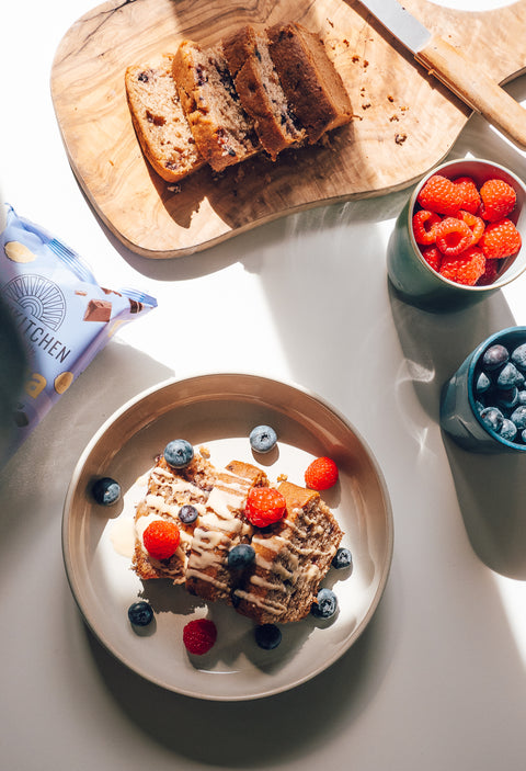 Hero section image with banana bread slices, fresh berries, and product packaging